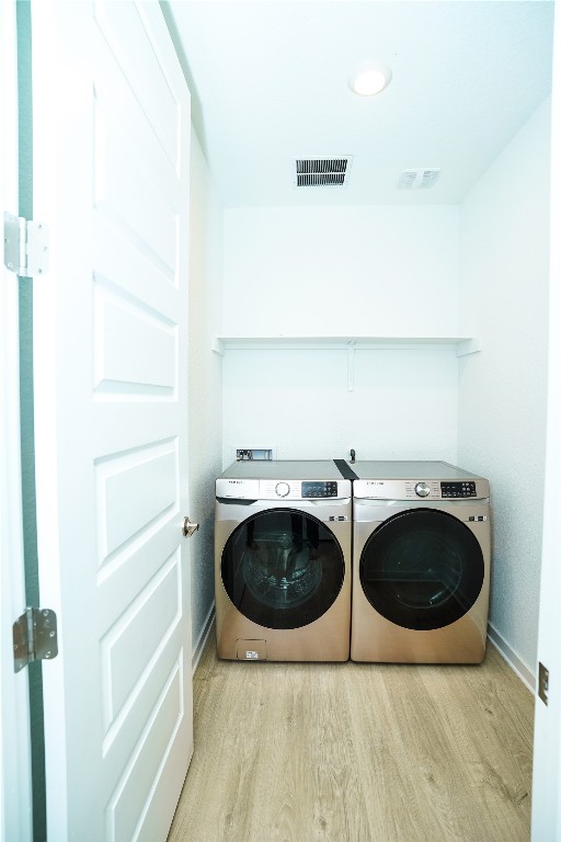 laundry room featuring washer and dryer and light hardwood / wood-style floors