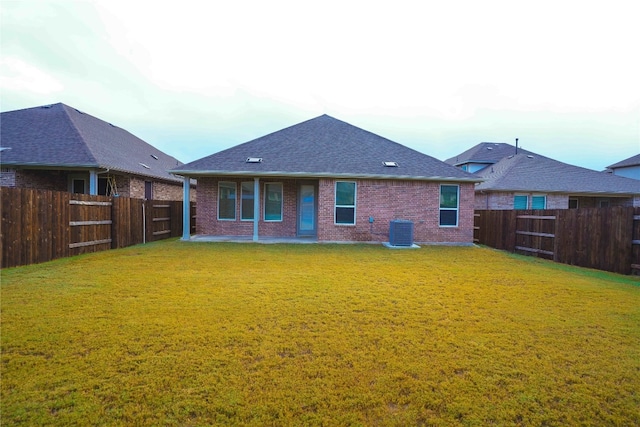 rear view of house featuring a yard and central air condition unit