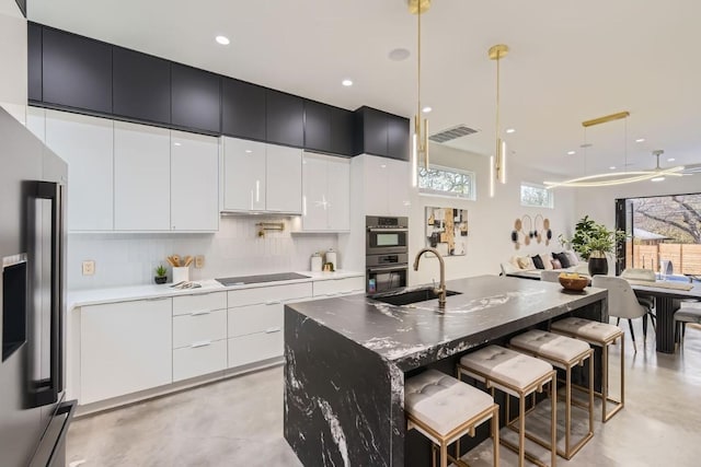 kitchen featuring sink, stainless steel appliances, a spacious island, a kitchen bar, and decorative light fixtures