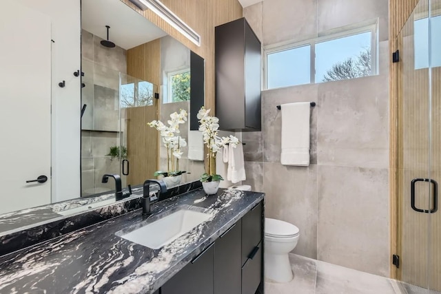 bathroom featuring vanity, toilet, an enclosed shower, and tile walls