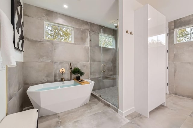 bathroom with shower with separate bathtub and tile walls