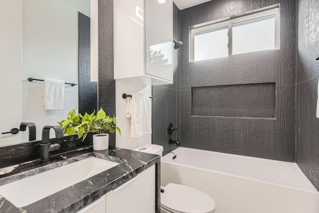 full bathroom featuring vanity, tiled shower / bath, and toilet