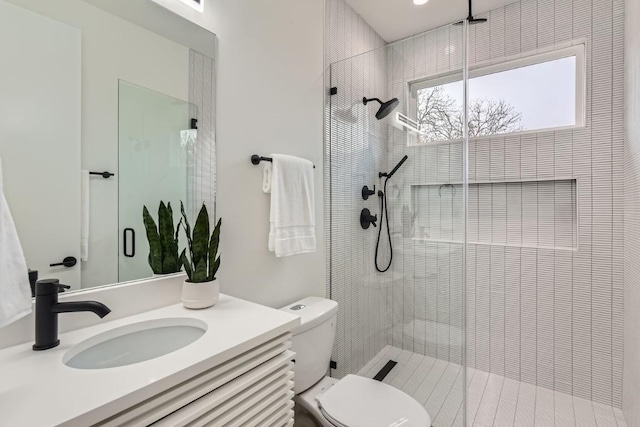 bathroom featuring vanity, an enclosed shower, and toilet