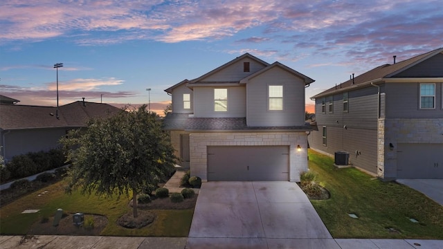 front of property featuring a yard, a garage, and central air condition unit