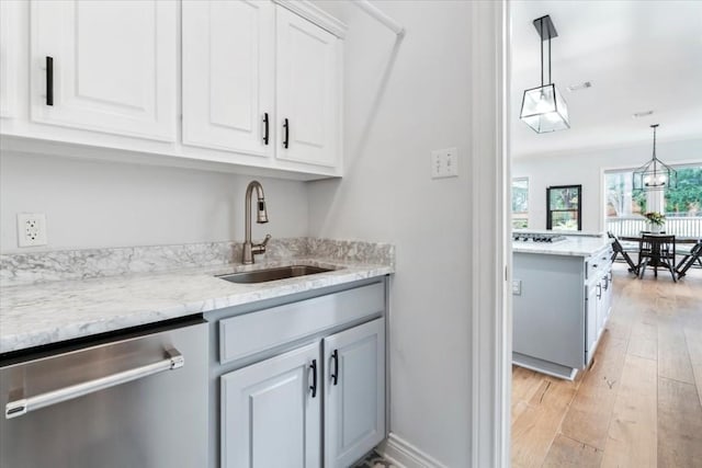 kitchen with light wood-type flooring, white cabinets, sink, dishwasher, and hanging light fixtures