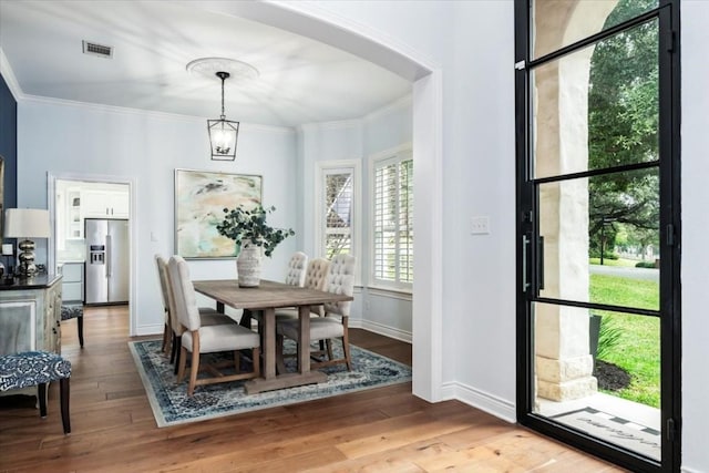 dining area featuring light wood-type flooring, ornamental molding, and a chandelier