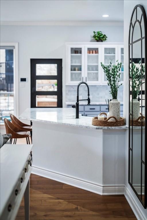 kitchen featuring a breakfast bar, dark hardwood / wood-style floors, white cabinetry, and light stone counters