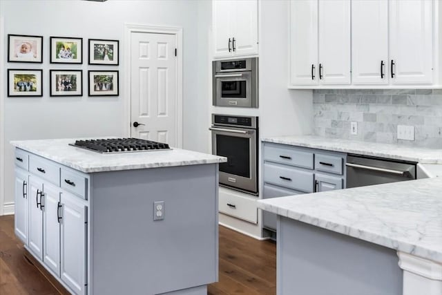 kitchen featuring white cabinets, stainless steel appliances, a kitchen island, and dark wood-type flooring