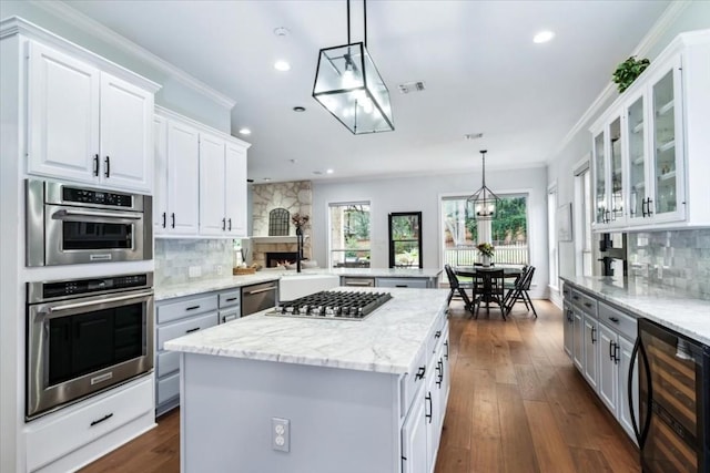 kitchen with white cabinets, pendant lighting, stainless steel appliances, and beverage cooler