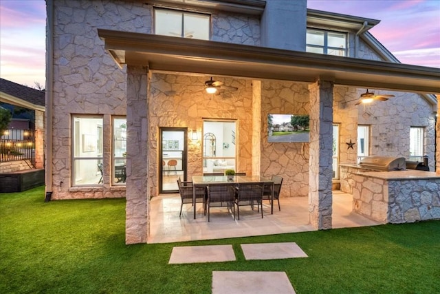 back house at dusk with a yard, area for grilling, and a patio area