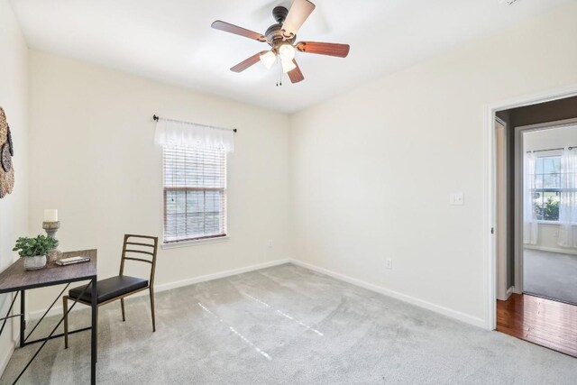 unfurnished office with ceiling fan, plenty of natural light, and light colored carpet