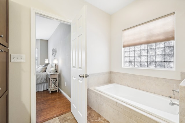 bathroom with hardwood / wood-style flooring and tiled bath