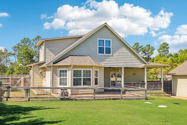 rear view of house with ceiling fan and a lawn