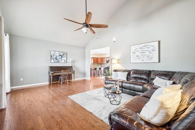 living room with ceiling fan, hardwood / wood-style floors, and high vaulted ceiling