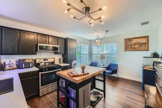 kitchen with a chandelier, dark wood-type flooring, hanging light fixtures, and appliances with stainless steel finishes