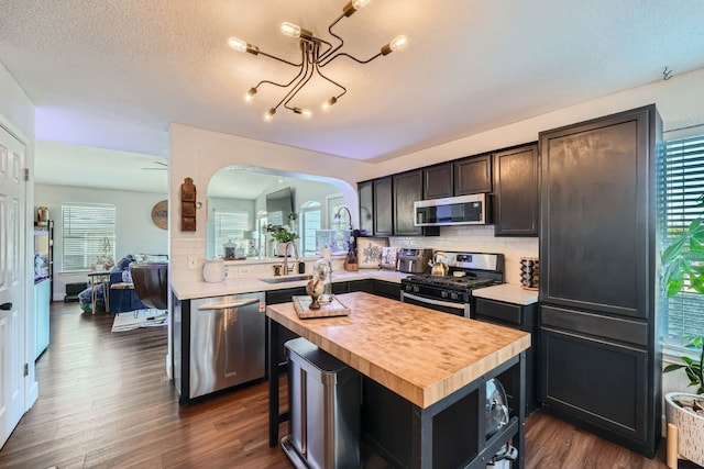 kitchen with dark hardwood / wood-style floors, a kitchen island, stainless steel appliances, and a wealth of natural light