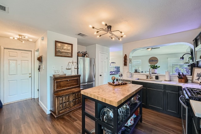 kitchen featuring dark hardwood / wood-style flooring, ceiling fan with notable chandelier, a textured ceiling, stainless steel appliances, and sink