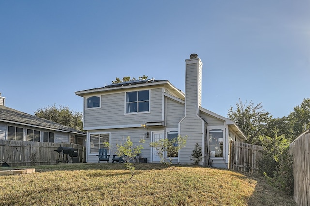 back of house with solar panels and a yard