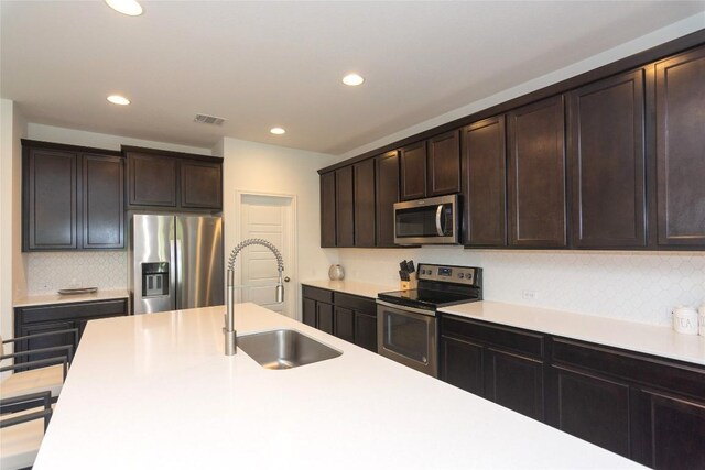 kitchen with backsplash, dark brown cabinetry, sink, and appliances with stainless steel finishes