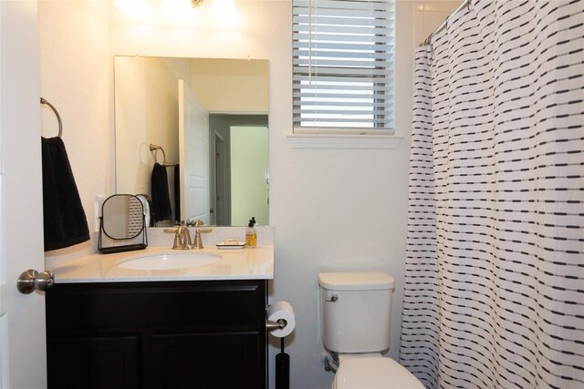 bathroom with walk in shower, vanity, and toilet