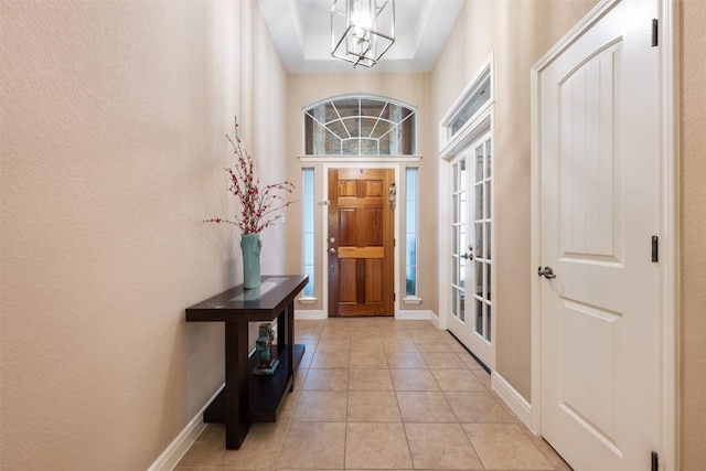 foyer with french doors, light tile patterned flooring, and a notable chandelier