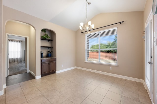 spare room with light tile patterned floors, a wealth of natural light, and vaulted ceiling