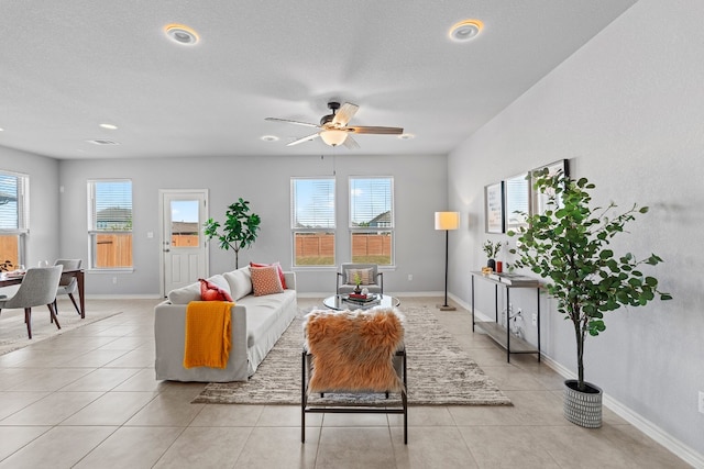 tiled living room with ceiling fan, a healthy amount of sunlight, and a textured ceiling