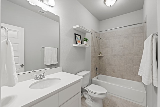 full bathroom featuring vanity, tile patterned floors, tiled shower / bath combo, toilet, and a textured ceiling