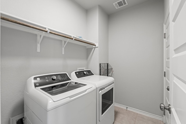 washroom with washing machine and clothes dryer and light tile patterned floors