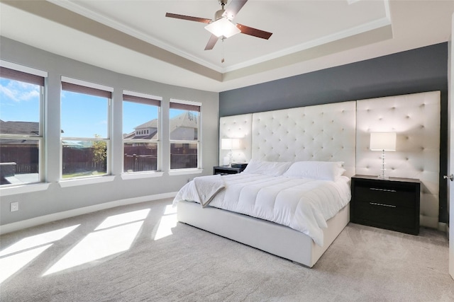 bedroom with ceiling fan, a raised ceiling, light carpet, and crown molding