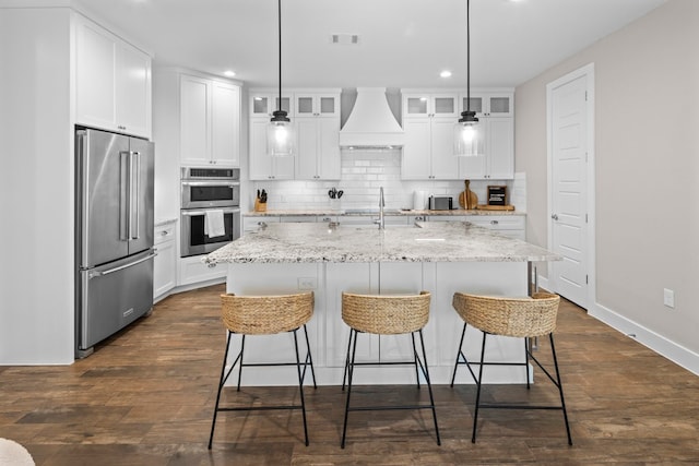 kitchen featuring white cabinetry, dark hardwood / wood-style floors, a kitchen island with sink, custom range hood, and appliances with stainless steel finishes