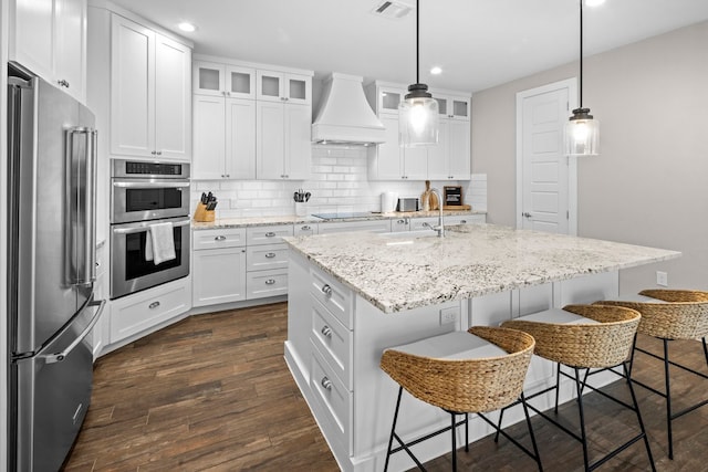 kitchen with white cabinets, custom range hood, and stainless steel appliances