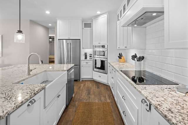 kitchen with white cabinets, hanging light fixtures, dark hardwood / wood-style floors, appliances with stainless steel finishes, and custom range hood