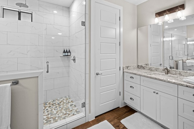 bathroom with wood-type flooring, vanity, and a shower with shower door