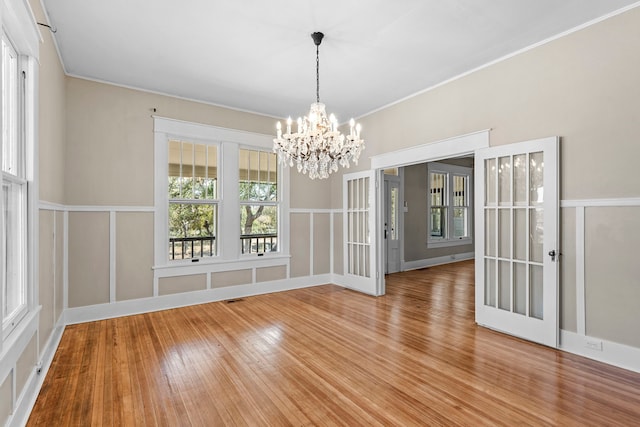 unfurnished dining area with an inviting chandelier and hardwood / wood-style flooring