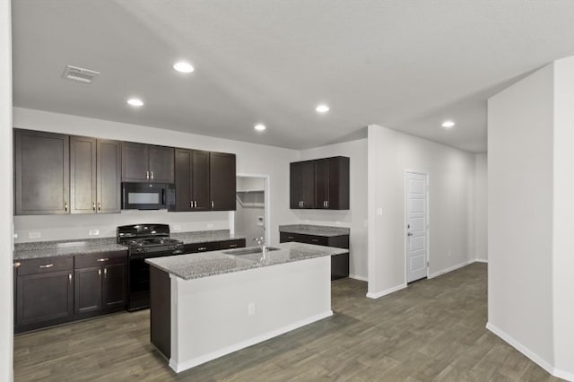 kitchen featuring an island with sink, dark brown cabinets, sink, and black appliances