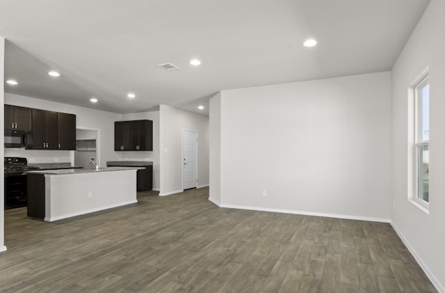 kitchen with dark wood finished floors, open floor plan, gas range oven, and black microwave