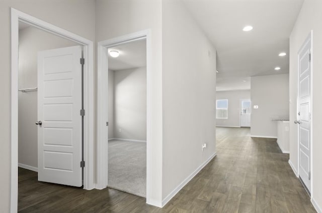 hallway with dark wood finished floors, recessed lighting, and baseboards