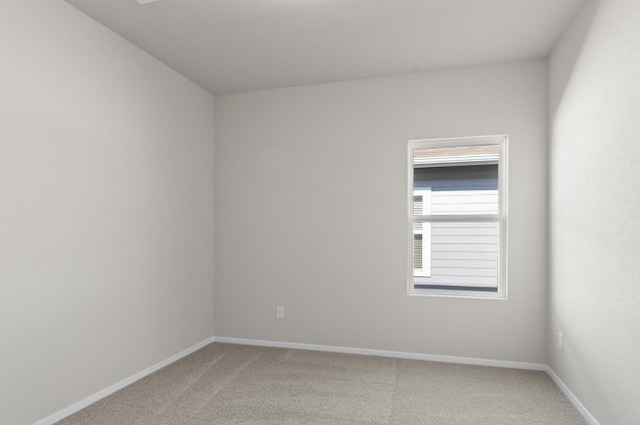 spare room featuring baseboards and light carpet