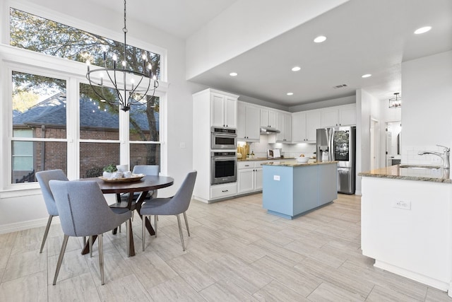 kitchen with light stone countertops, appliances with stainless steel finishes, white cabinetry, and sink