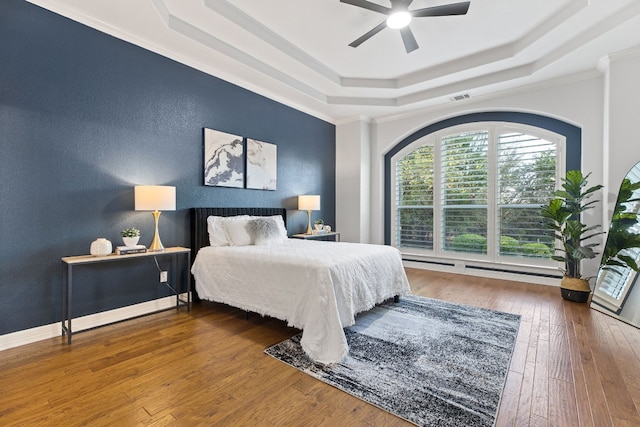 bedroom with ceiling fan, wood-type flooring, crown molding, and a tray ceiling