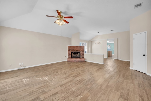 unfurnished living room featuring ceiling fan with notable chandelier, light wood-type flooring, a brick fireplace, and lofted ceiling