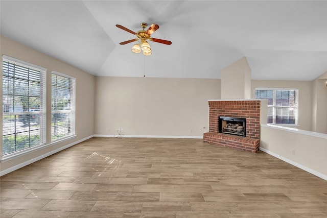 unfurnished living room featuring plenty of natural light, ceiling fan, lofted ceiling, and a fireplace