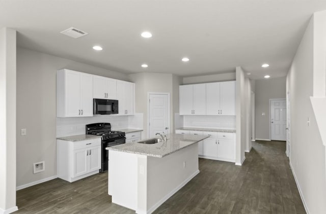 kitchen featuring sink, white cabinetry, light stone countertops, black appliances, and an island with sink