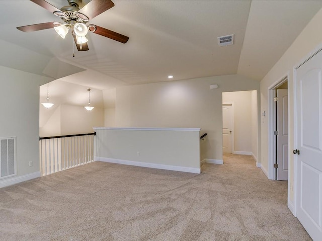 unfurnished room with visible vents, vaulted ceiling, light carpet, and baseboards