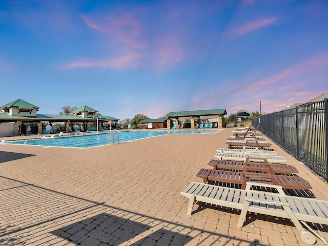 community pool with a patio area, fence, and a gazebo