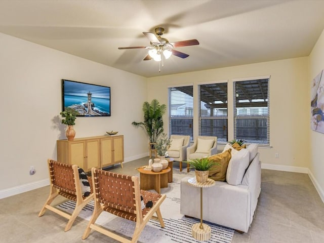 living area featuring light tile patterned flooring, ceiling fan, and baseboards