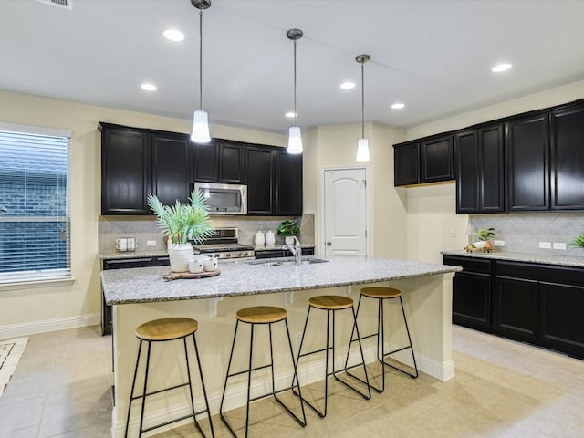 kitchen with an island with sink, appliances with stainless steel finishes, and hanging light fixtures