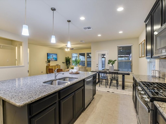 kitchen with pendant lighting, a center island with sink, visible vents, appliances with stainless steel finishes, and a sink