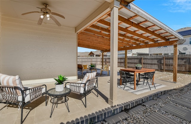 view of patio with a ceiling fan, outdoor dining area, and fence